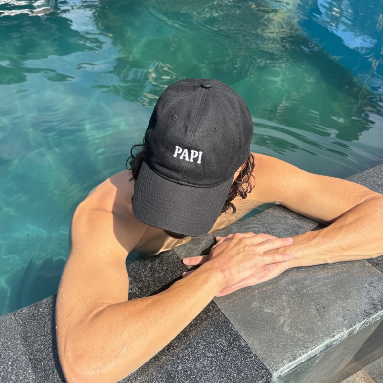 Person wearing a black cap with 'PAPI' text by a pool