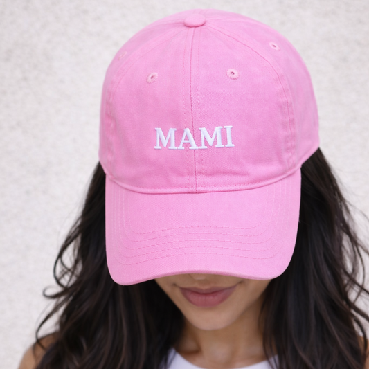 Pink cap with 'MAMI' text worn by a person against a neutral background